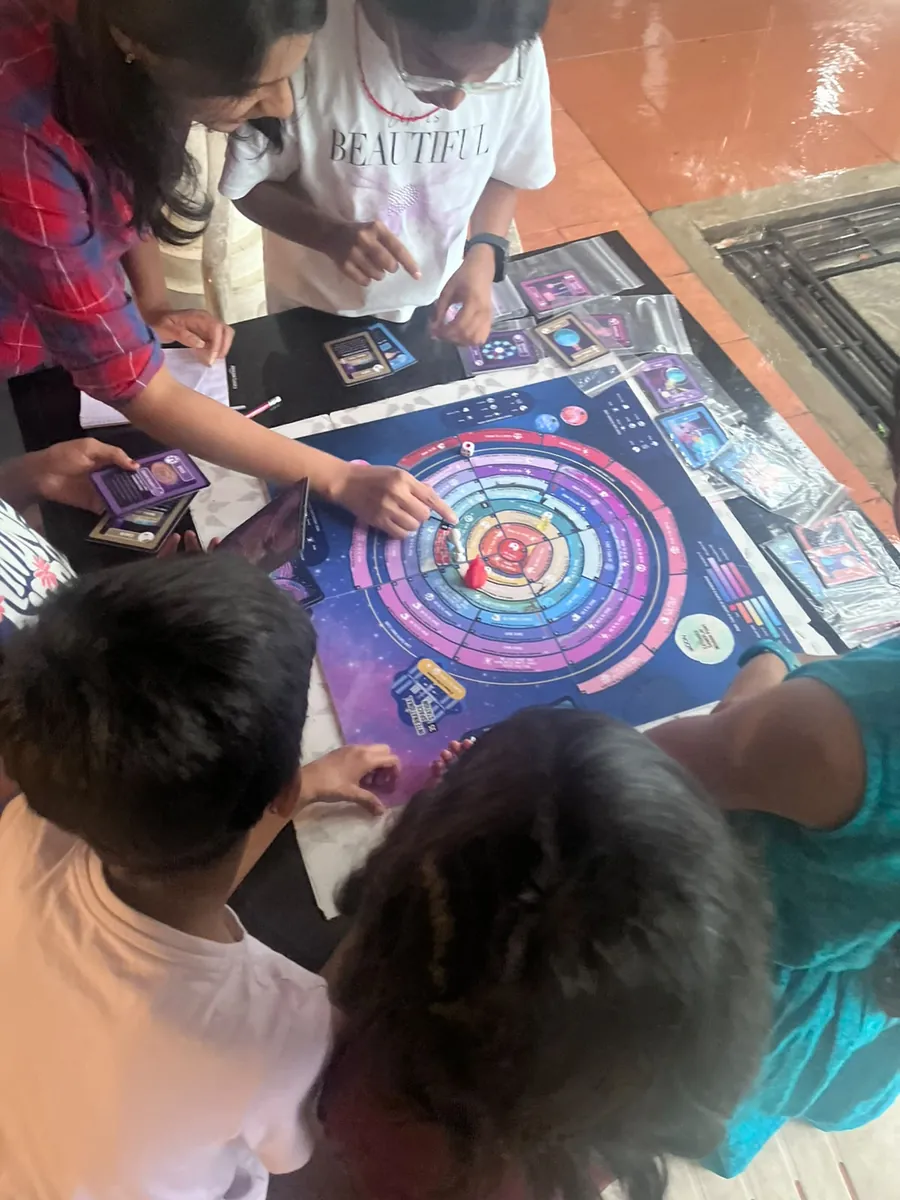 Children and parents playing the EscapeGravity science board game together on the floor