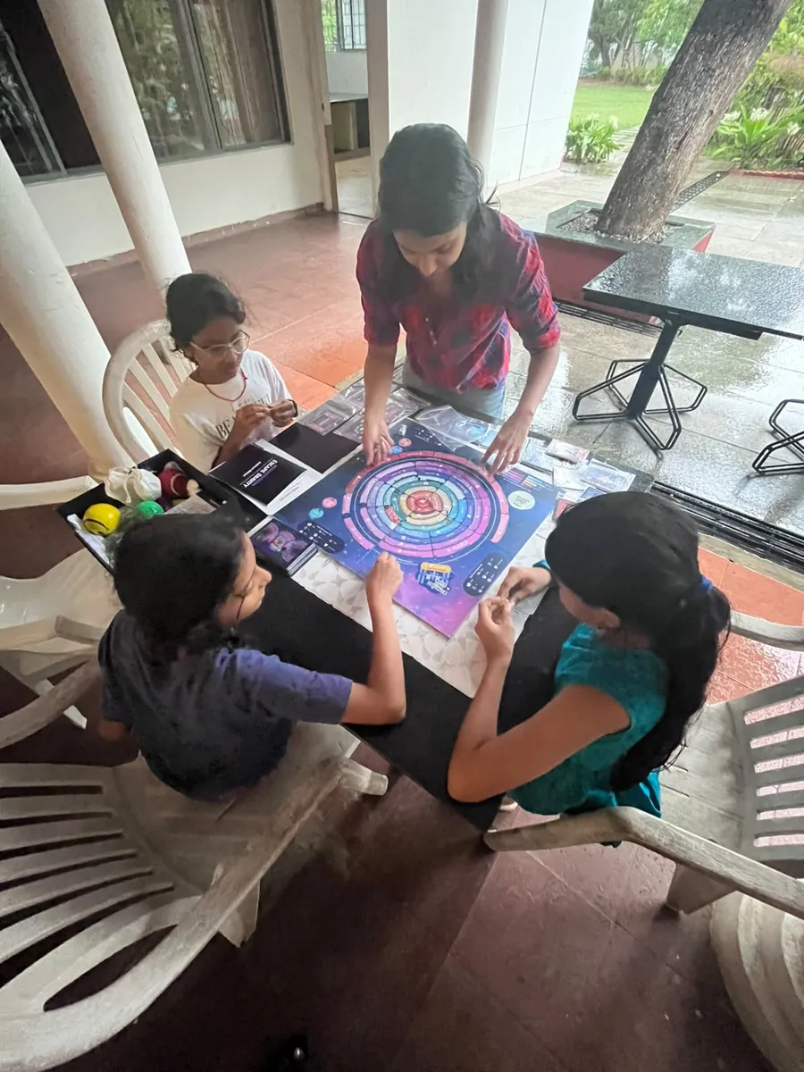 A family playing EscapeGravity on a veranda table — a screen-free after-school activity