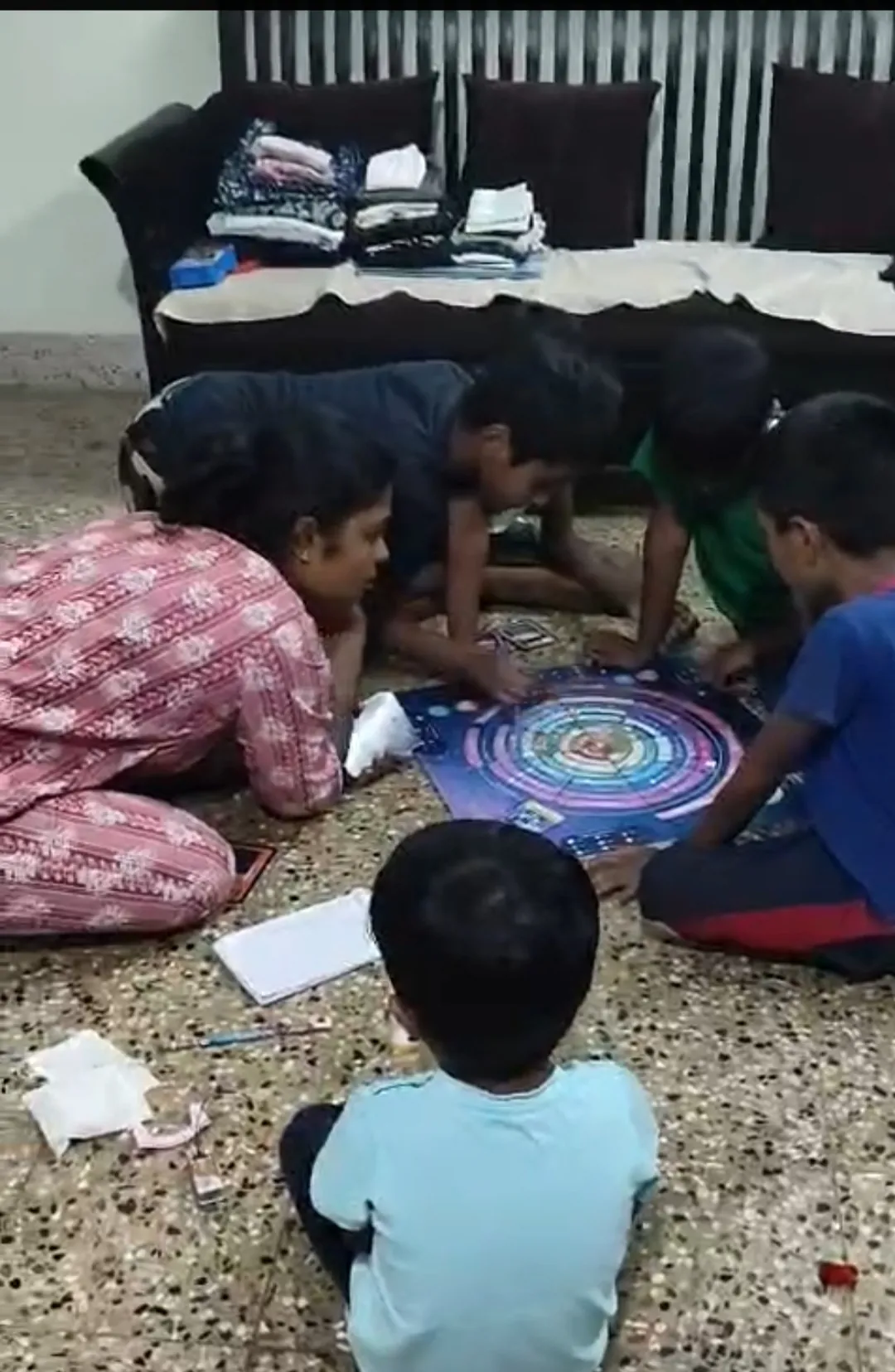 Five children playing the EscapeGravity board game on the floor at home